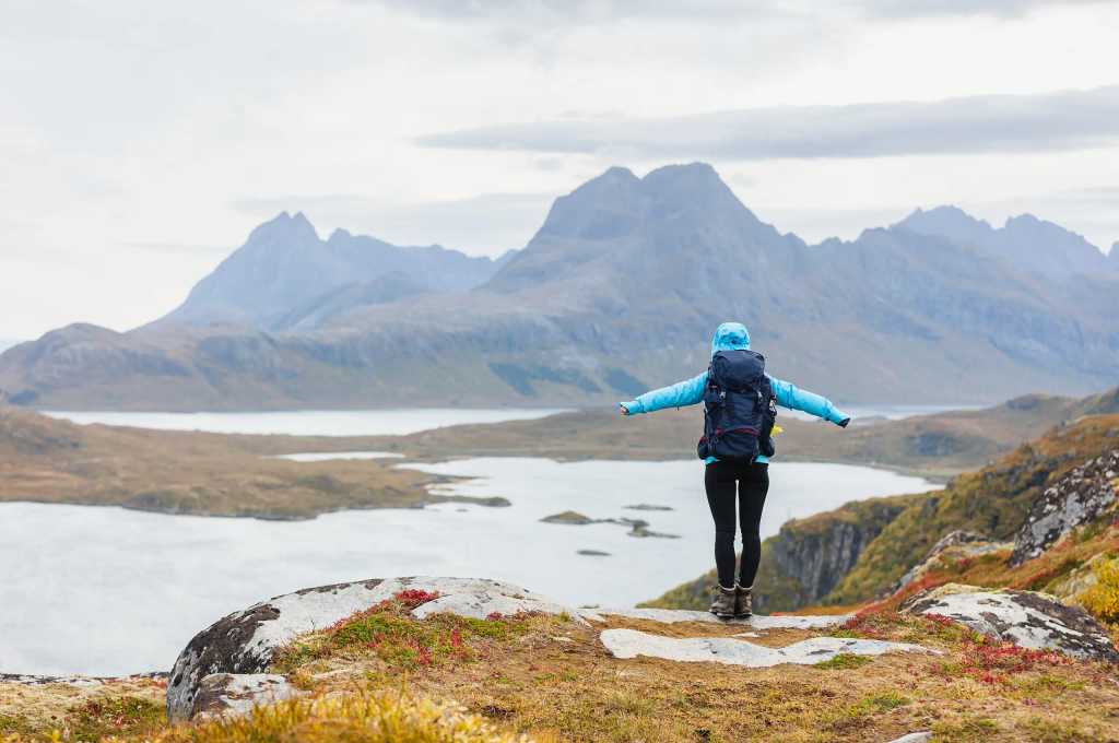 Vandrare med ryggsäck njuter av utsikten på toppen av en bergstopp.