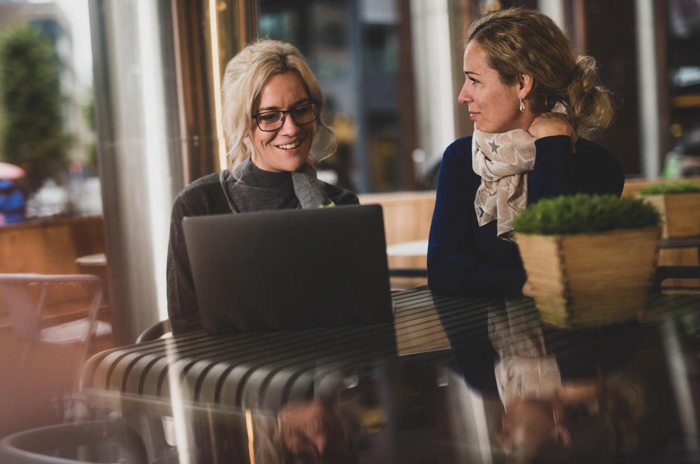 Två personer i trevligt samtal med var sin laptop.