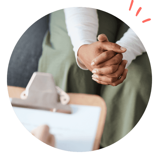 en person sitter med knäppta händer under en undersökning