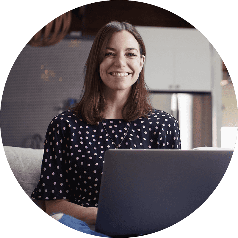 Glad kvinna som arbetar på sin laptop i soffan