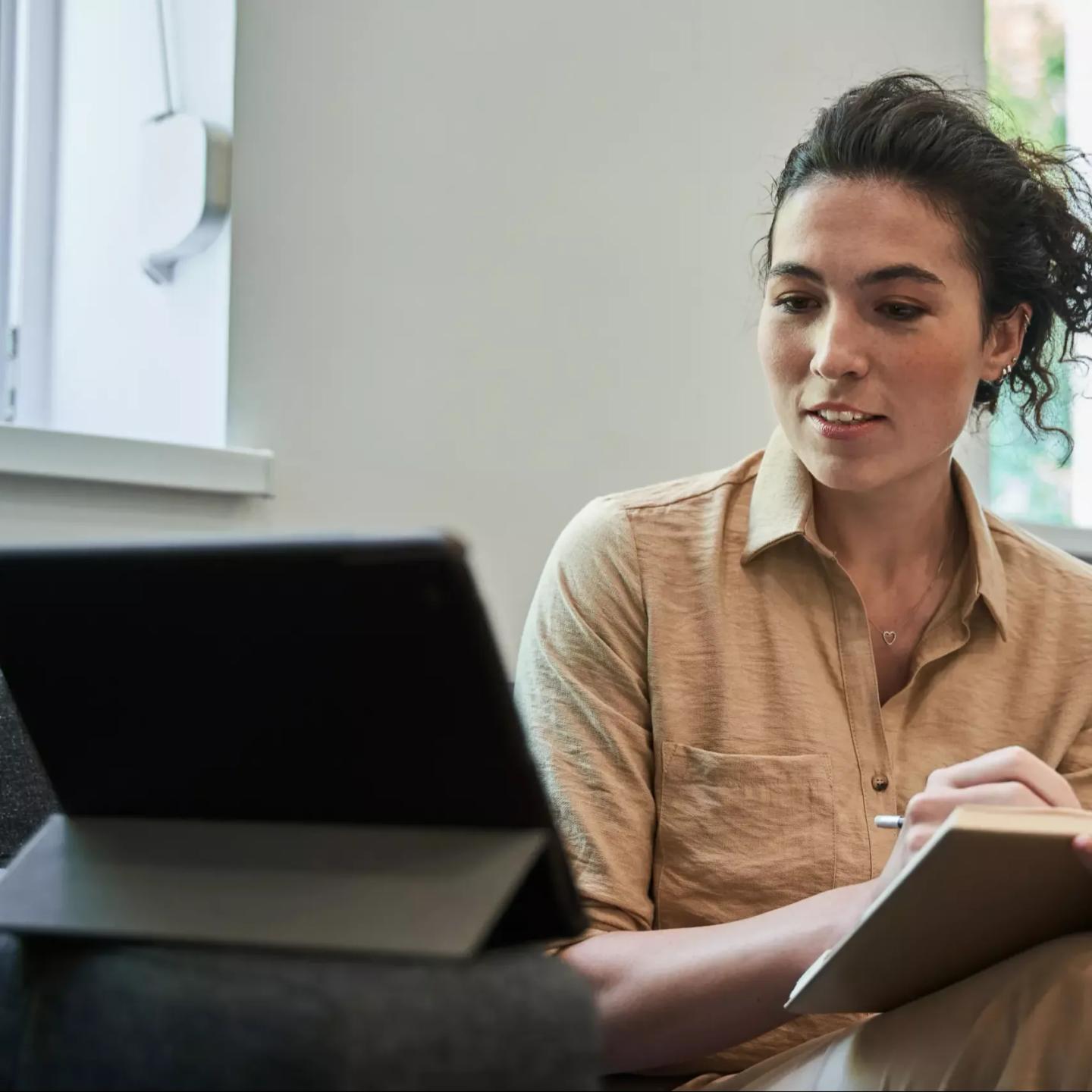 Inspirerad kvinna deltar i digitalt möte från sitt eget vardagsrum.