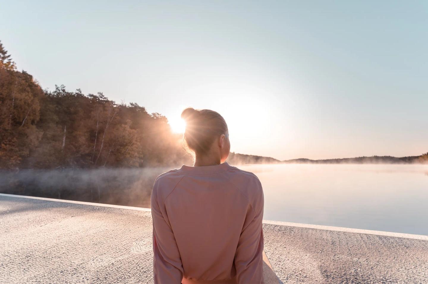 Ung person på en yogamatta vid havet en solig höstmorgon.