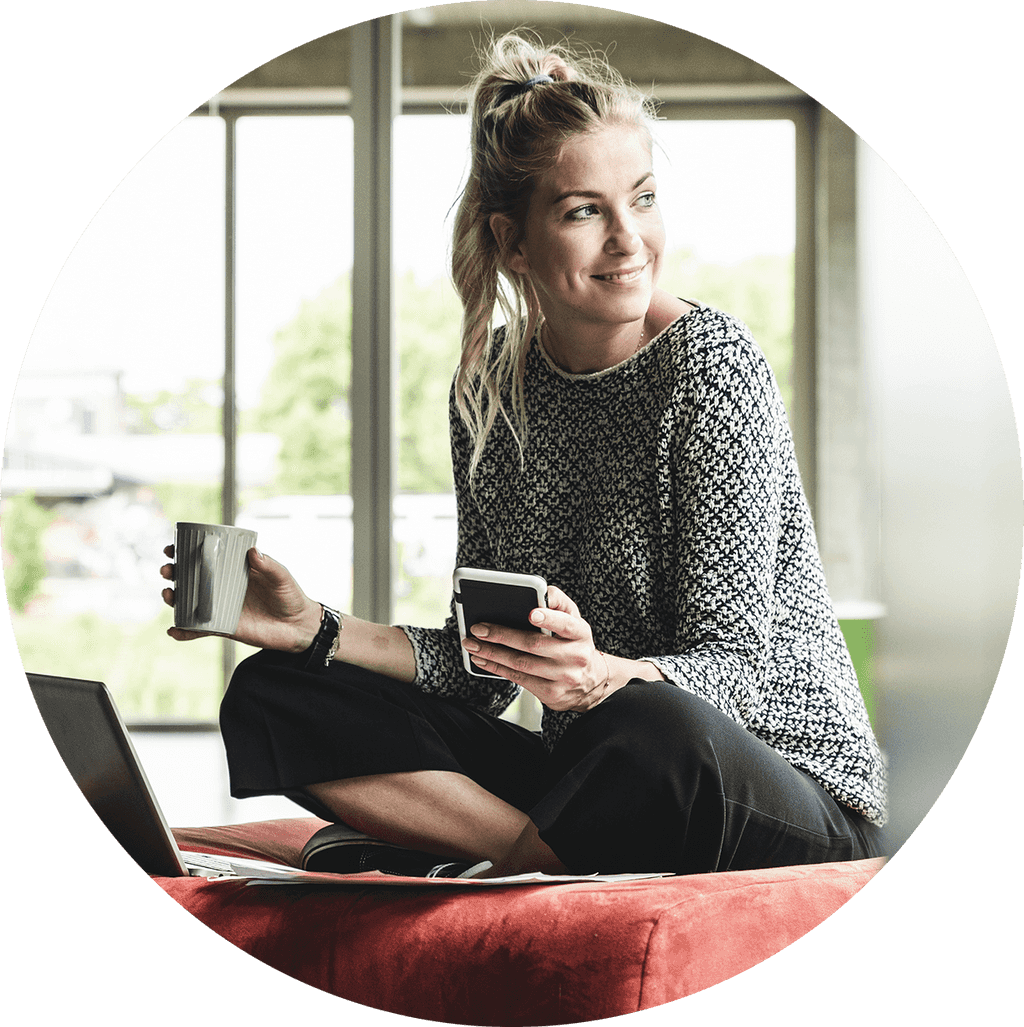 Kvinna på arbetet på sittpuff med dator och kaffe